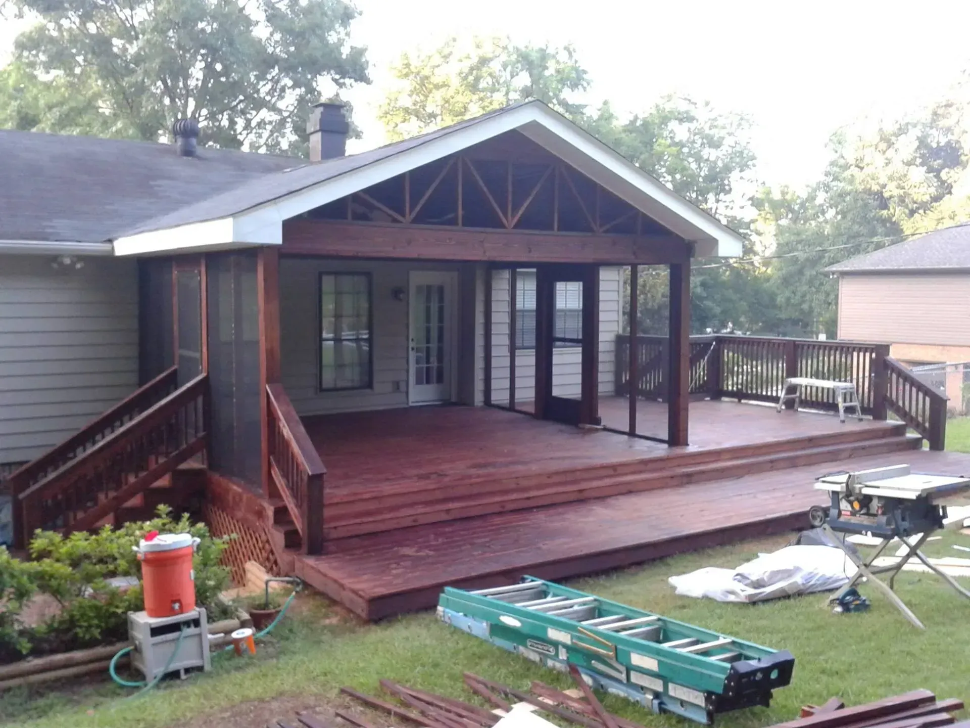 A screened in porch is being built in the backyard of a house