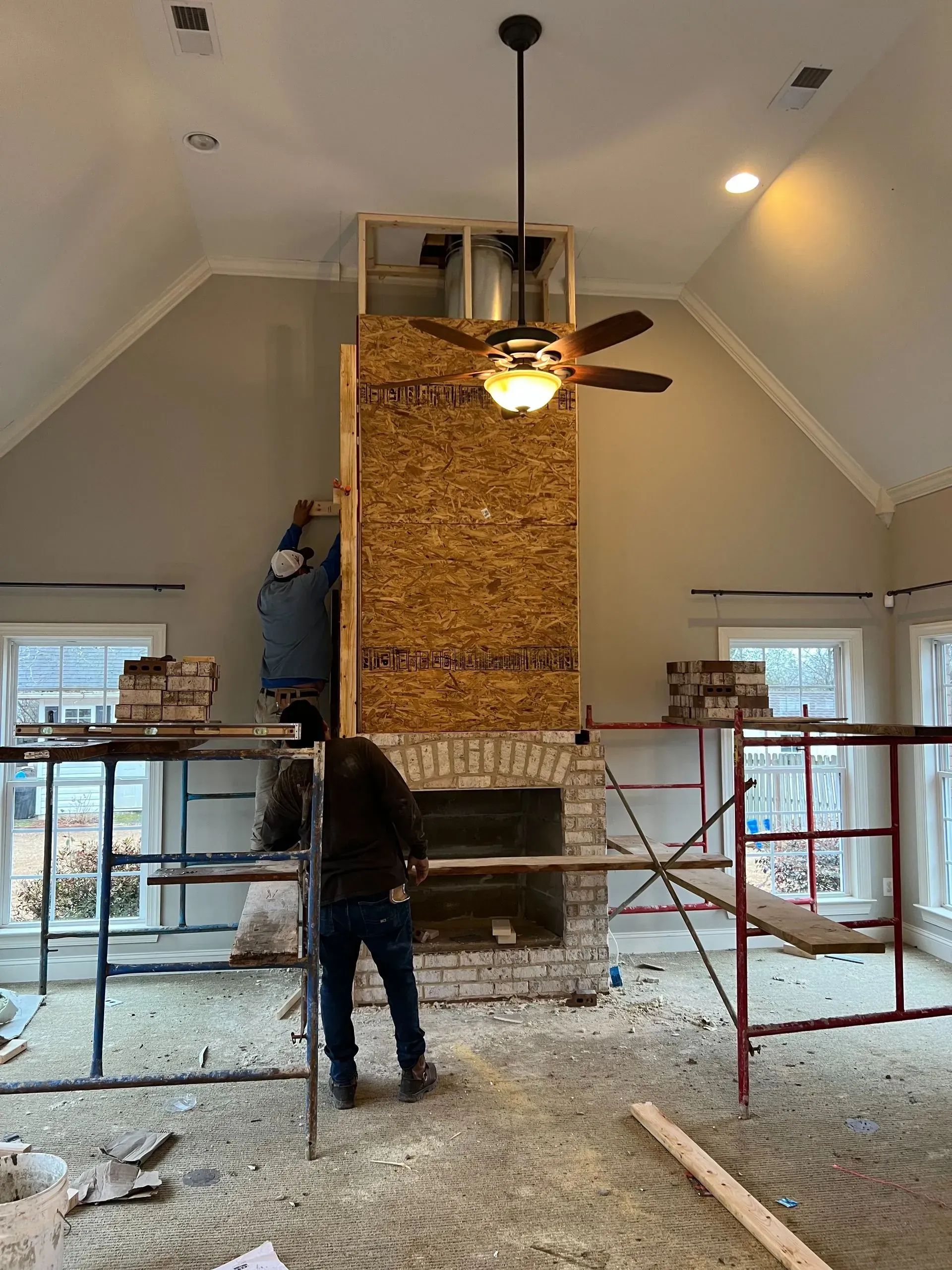 A man is working on a fireplace in a living room.