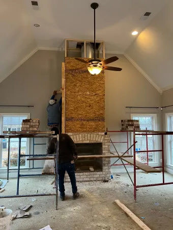 A man is working on a fireplace in a living room.