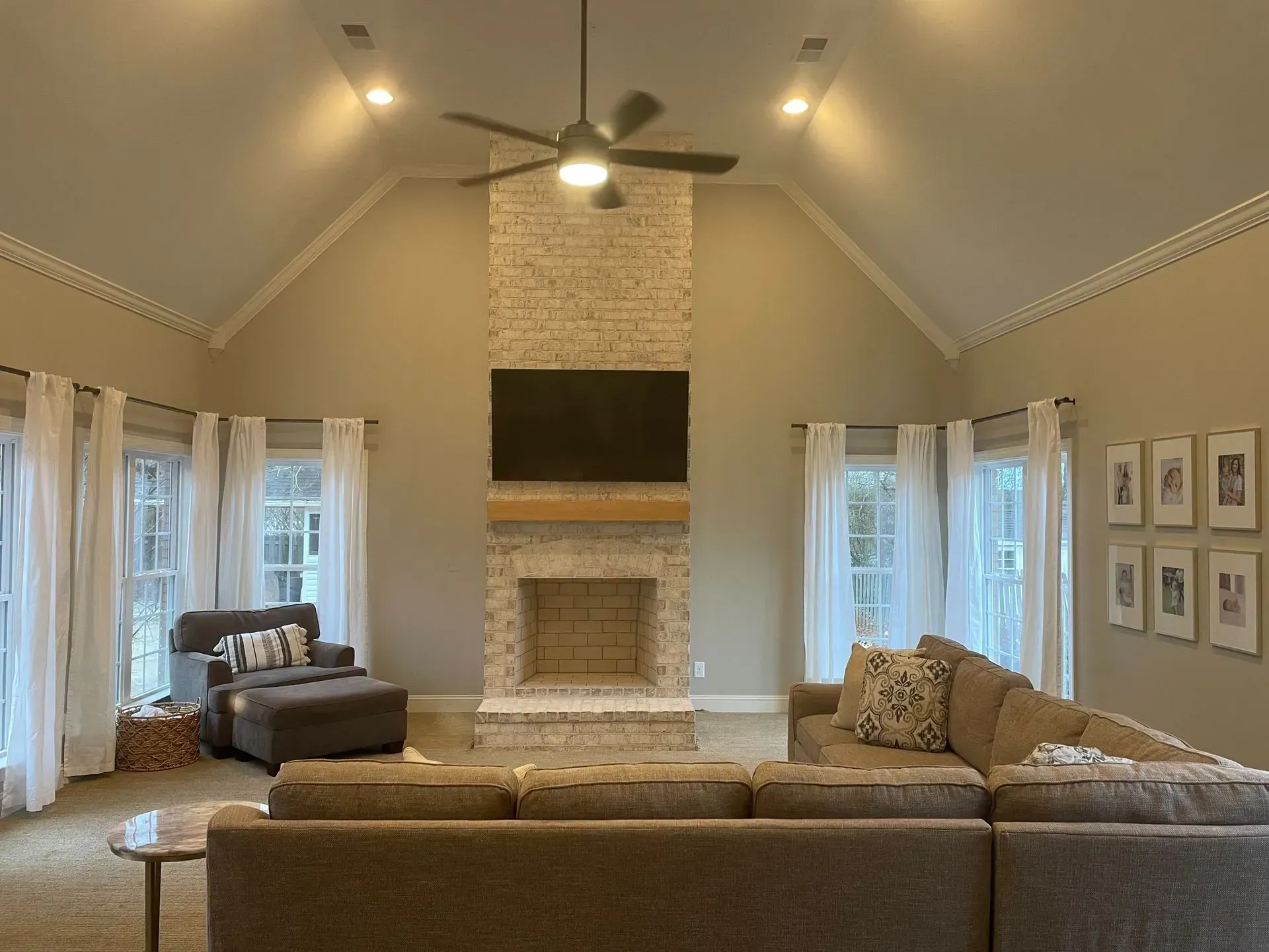 A living room with a couch , fireplace , television and ceiling fan.
