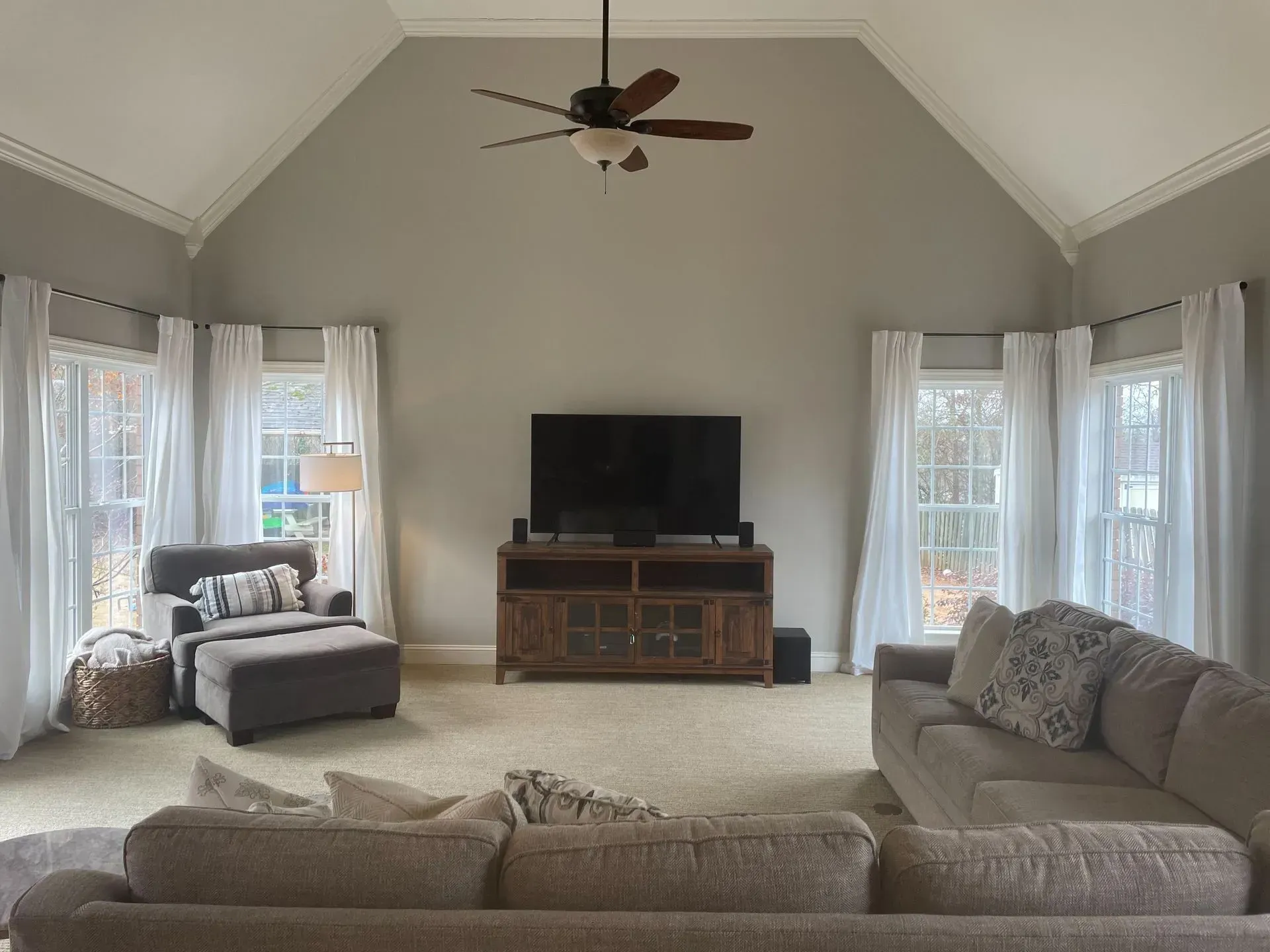 A living room with a couch , chair , television and ceiling fan.