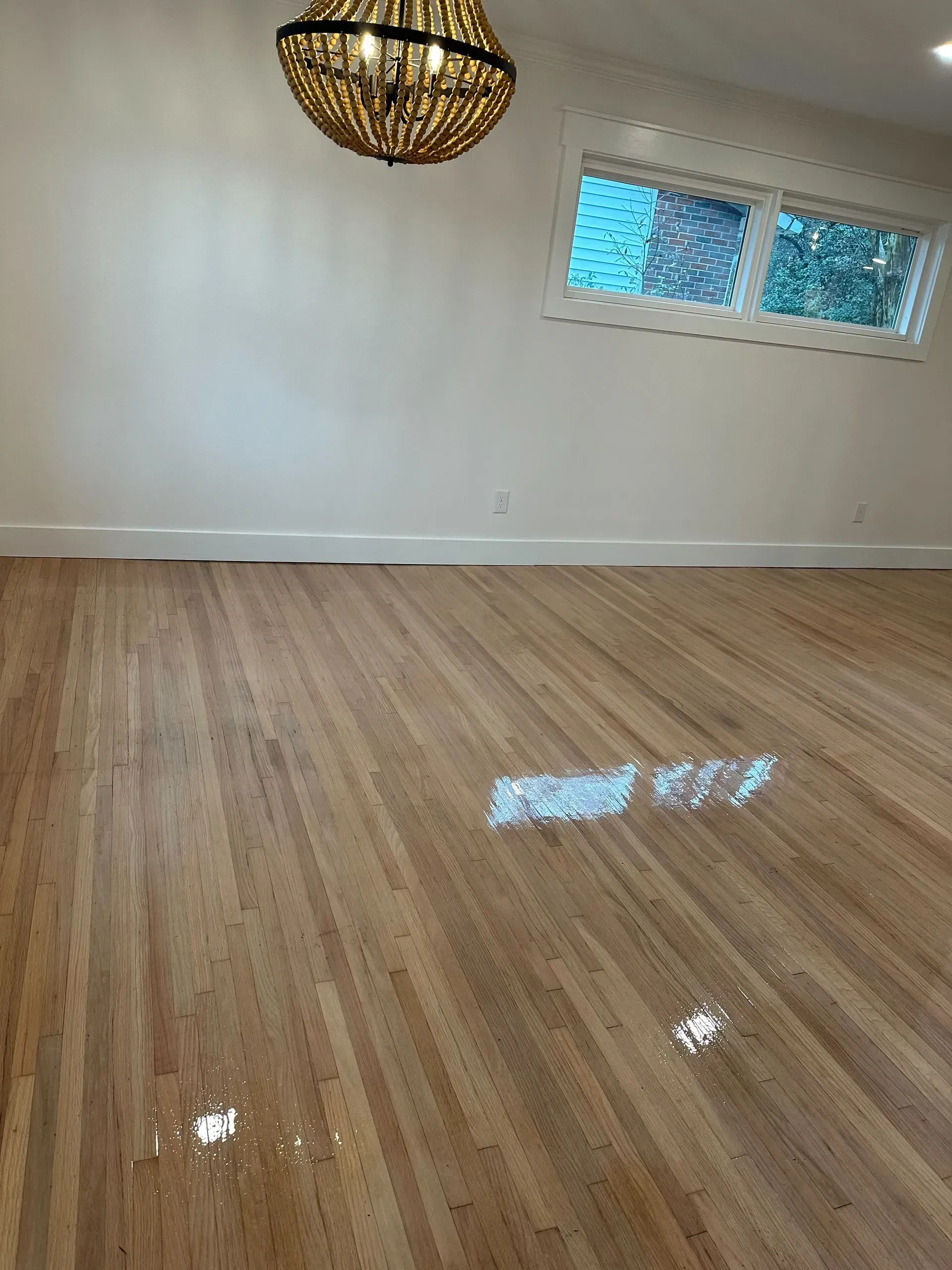 An empty room with a wooden floor and a chandelier hanging from the ceiling.