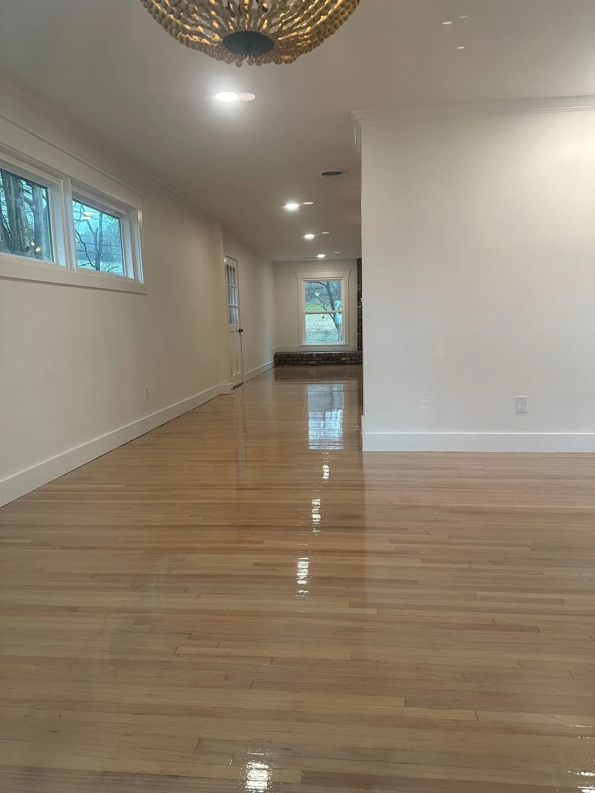 A large empty room with hardwood floors and white walls.