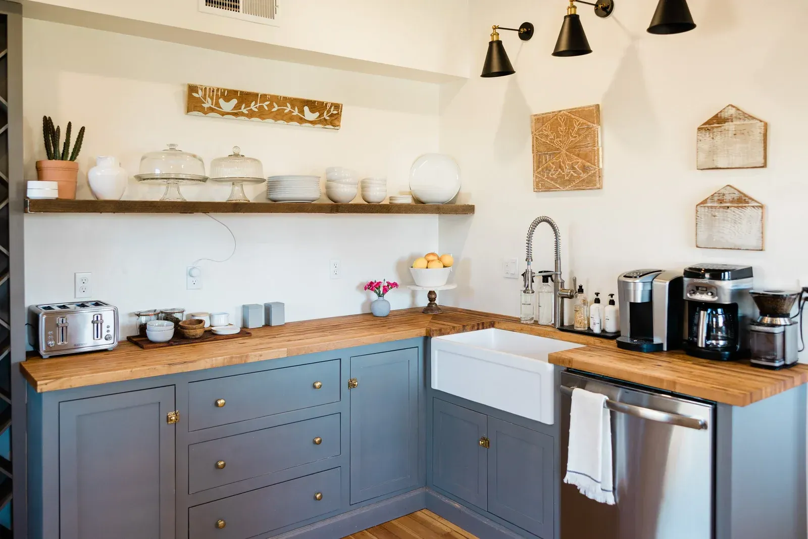A cozy, modern kitchen with gray cabinets, wooden countertops, and a farmhouse sink.