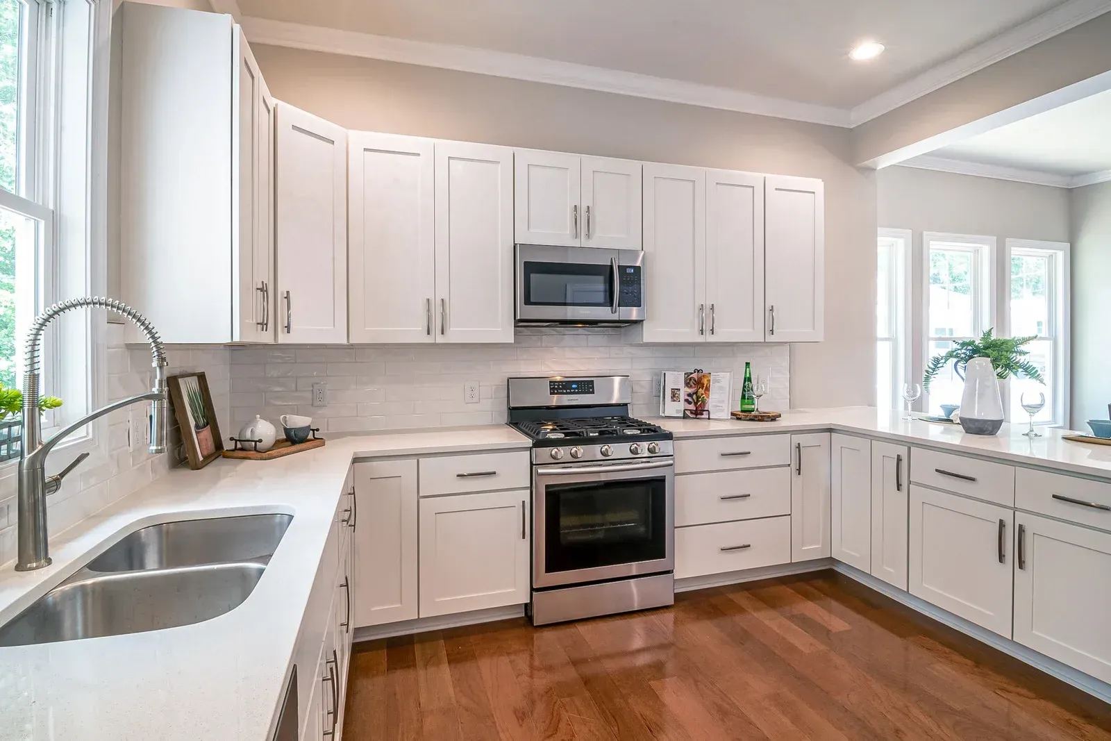 White kitchen with stainless steel appliances, white cabinets, and wood floors.