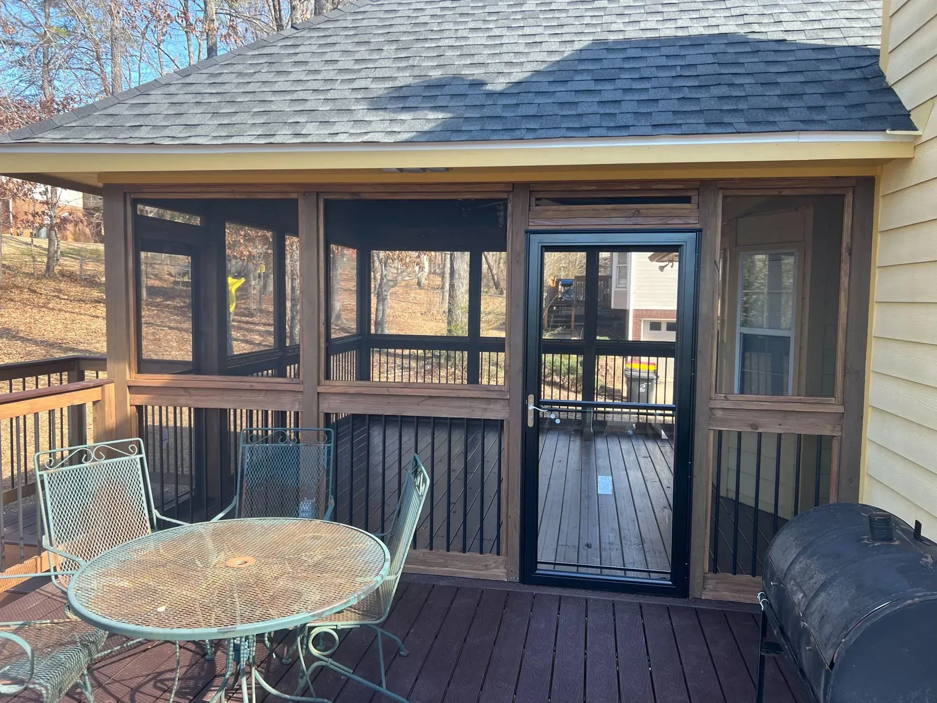 A screened in porch with a table and chairs and a grill.
