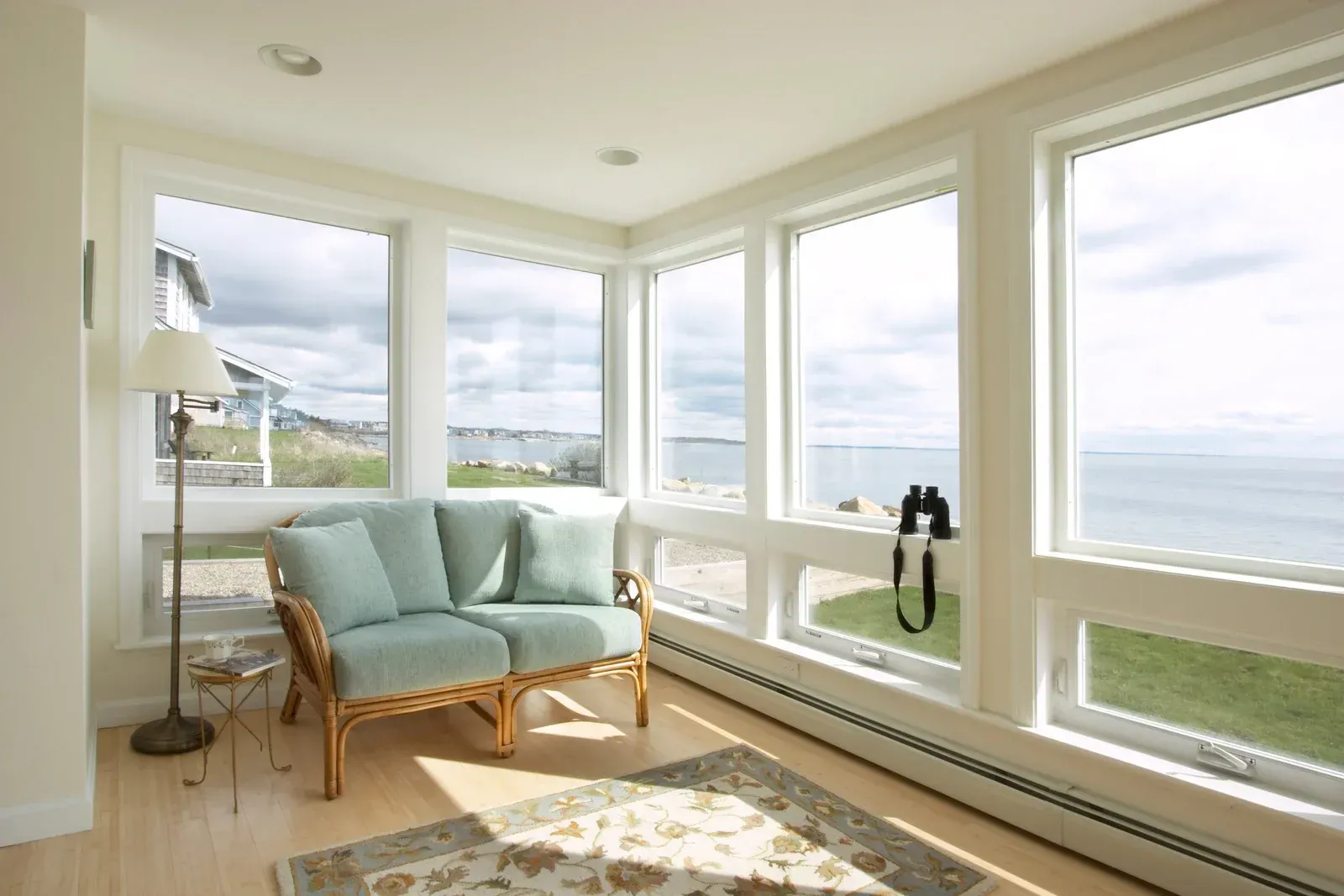 A living room with a couch and lots of windows overlooking the ocean.