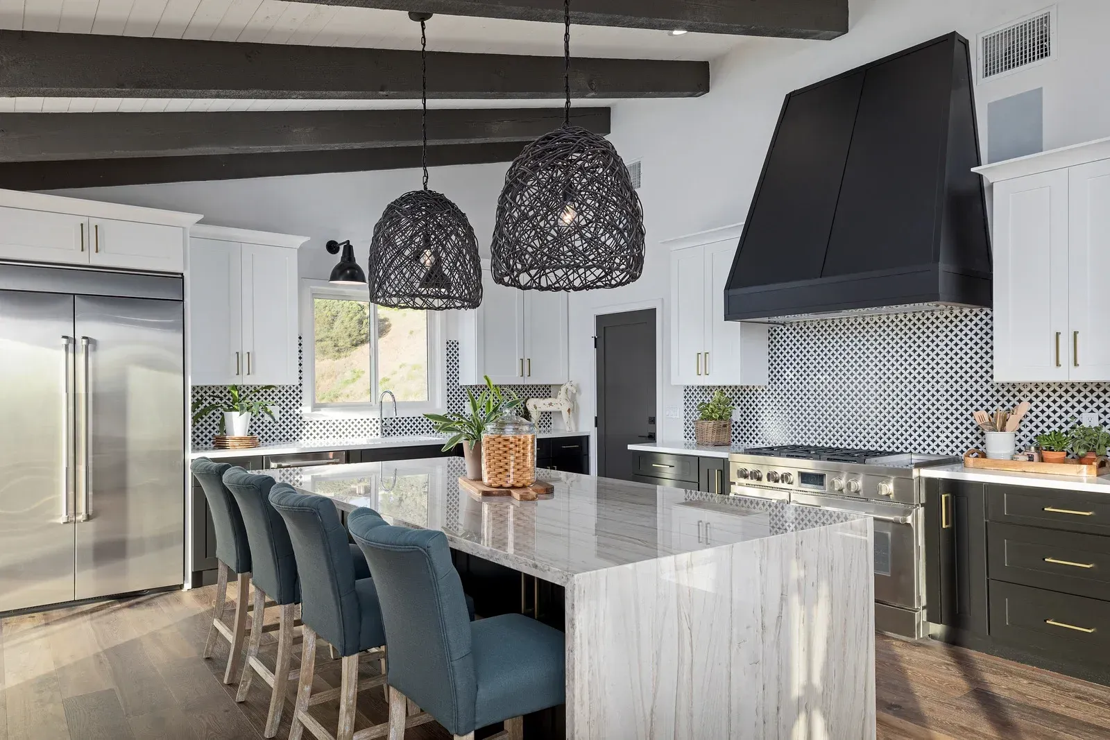 A kitchen with white cabinets , stainless steel appliances , a large island , and blue chairs.