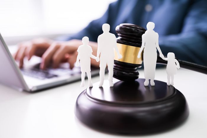 A man is typing on a laptop next to a gavel with a family on it.