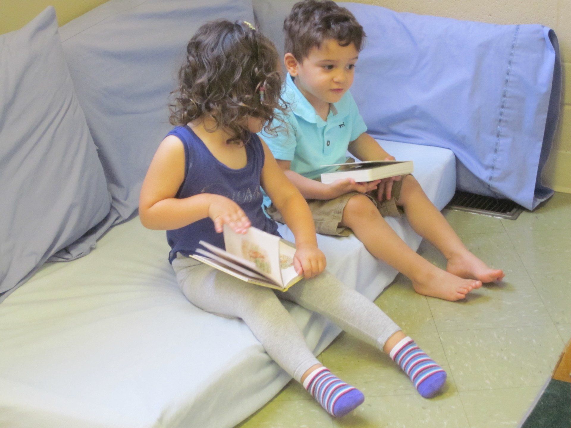 Two young children sitting together, reading books.