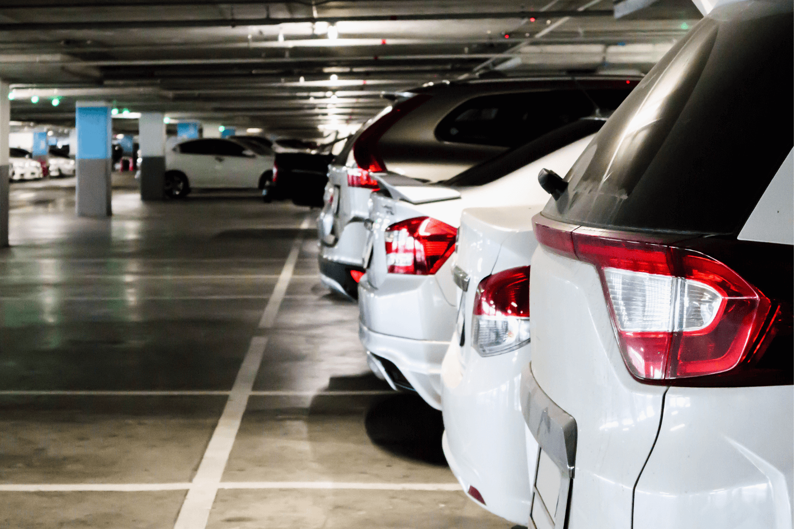 Construction worker kneeling, using a trowel to smooth concrete in a road joint, wearing orange vest and gloves.