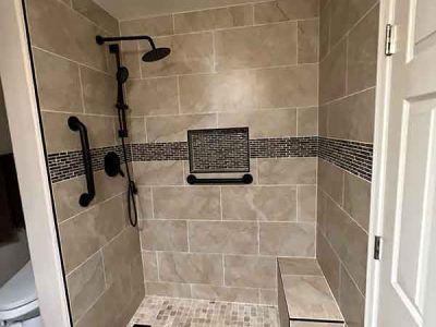 A walk in shower with a bench and a shower head.