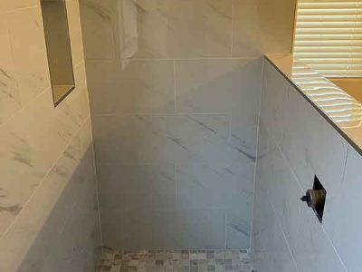 A bathroom with a walk in shower and a sink.