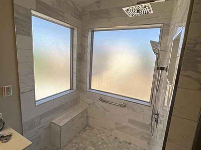 A bathroom with a walk in shower and a large window.