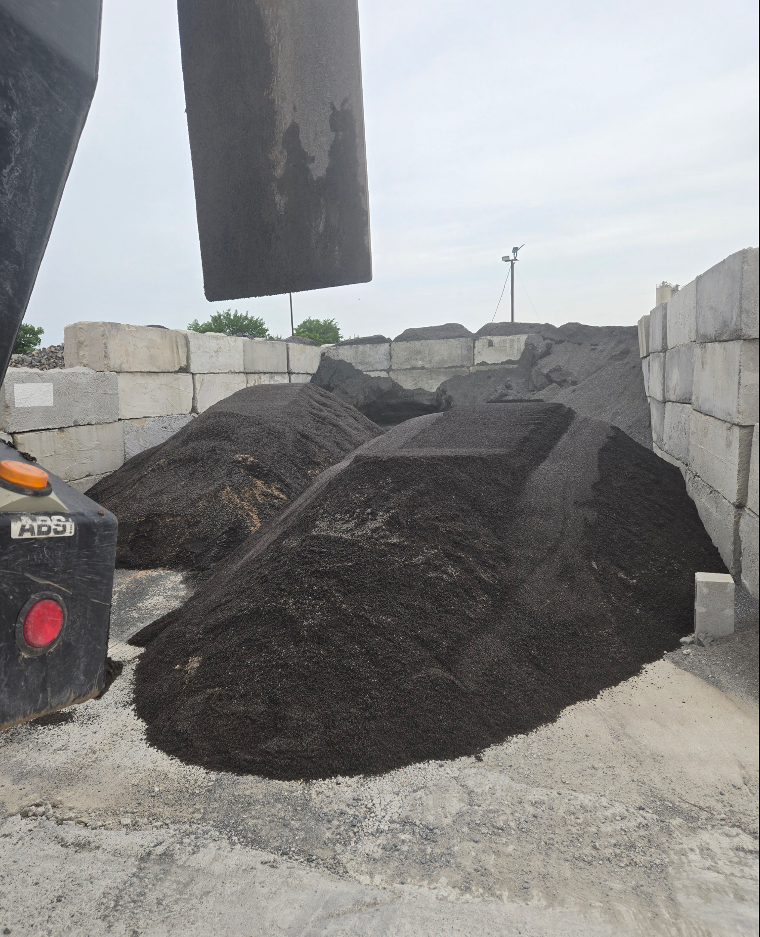 A pile of black decomposed granite sitting on top of a pile of gravel
