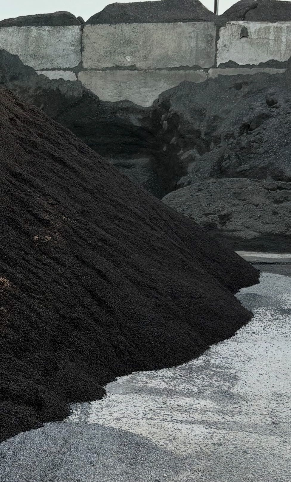 A pile of coal is sitting on top of a pile of gravel.