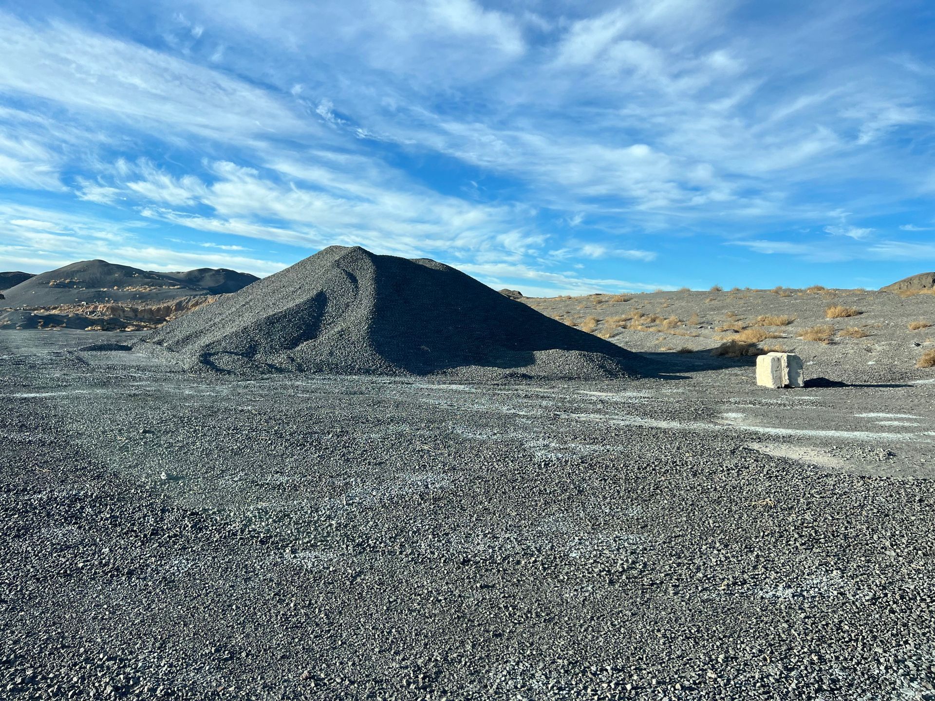 A large pile of gravel is sitting in the middle of a dirt field.