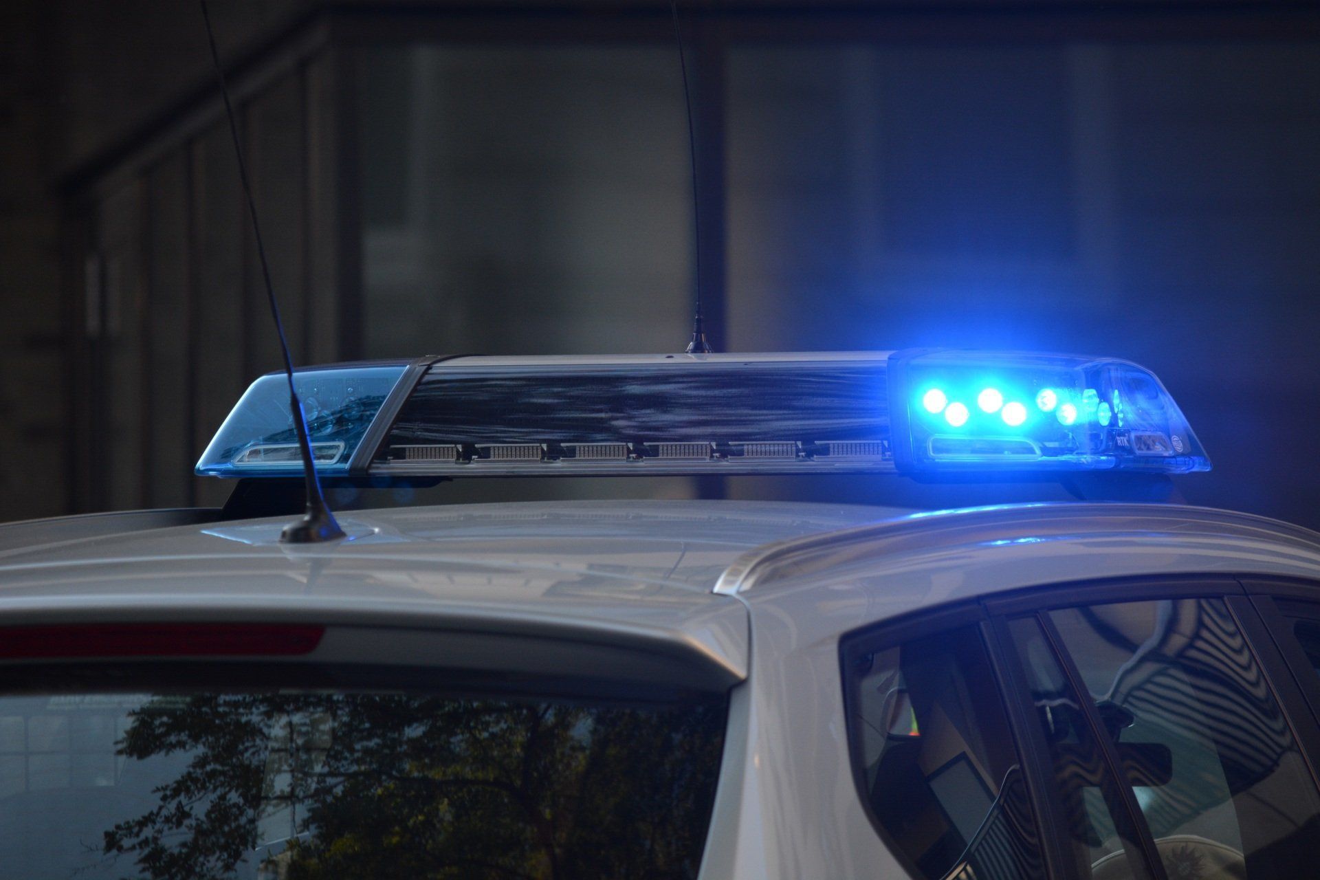 Blue police lights flashing on top of a parked white patrol car