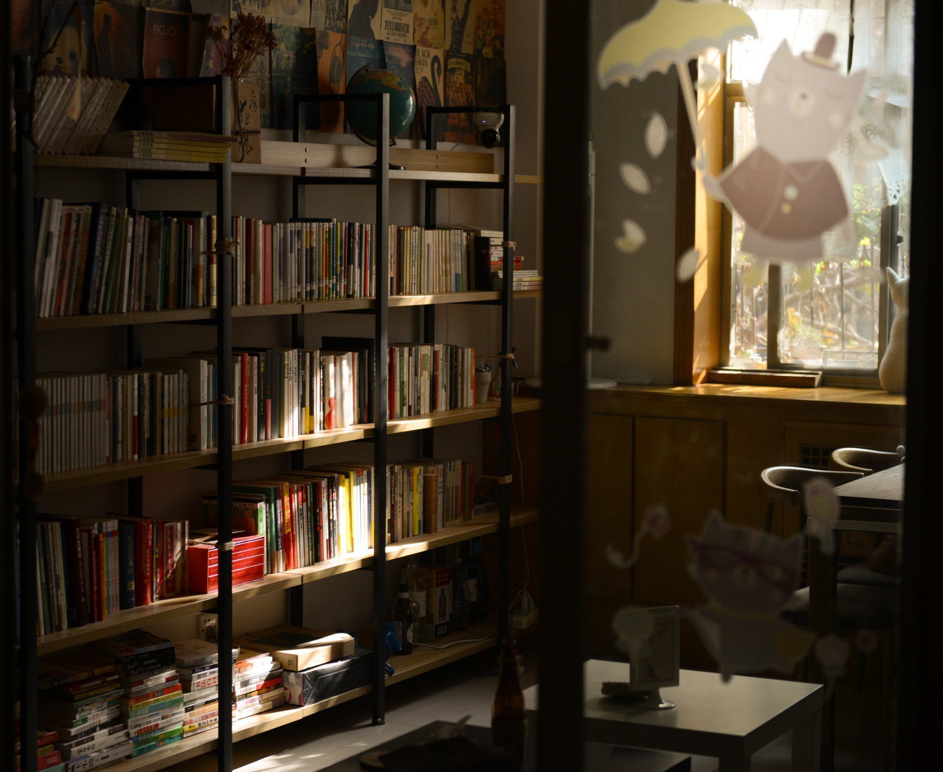 Sunlit room with bookshelves and a window, casting patterned light onto a table and chair