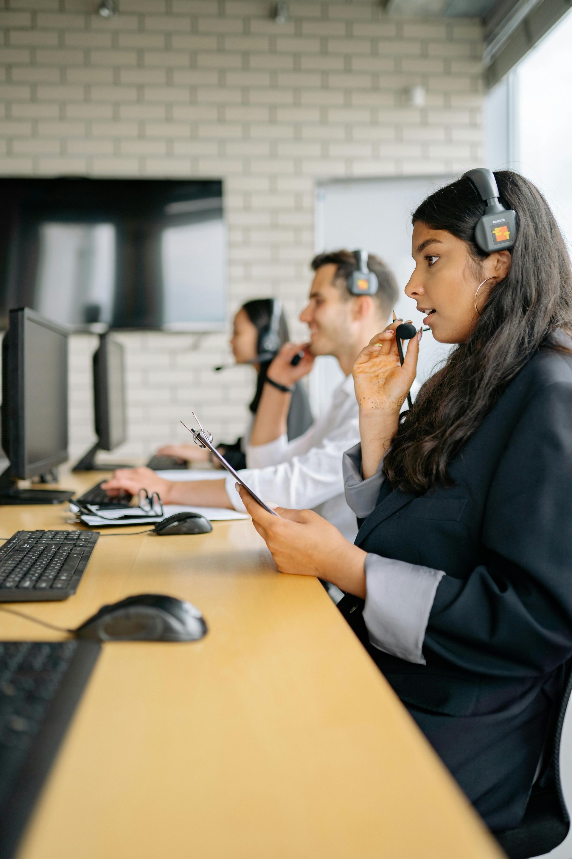 Call center agents wearing headsets working at computers in an office