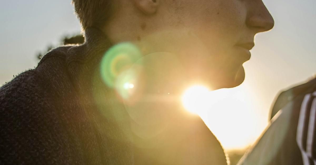Silhouette of a person in profile at sunset with sun flare in the background