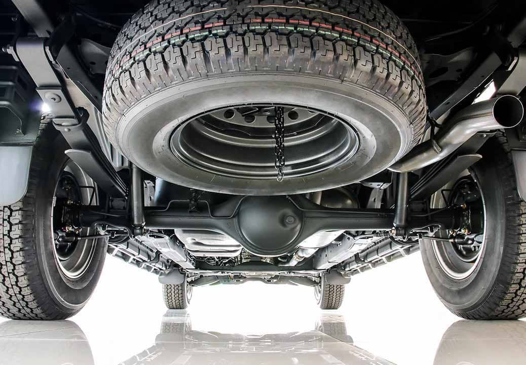 The underside of a truck with a spare tire attached to it.