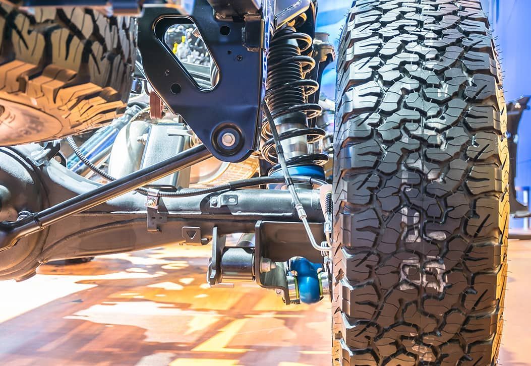 A close up of a truck 's suspension and tire.