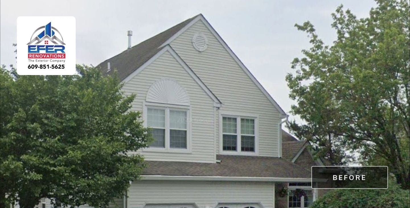 A white house with a brown roof is surrounded by trees.