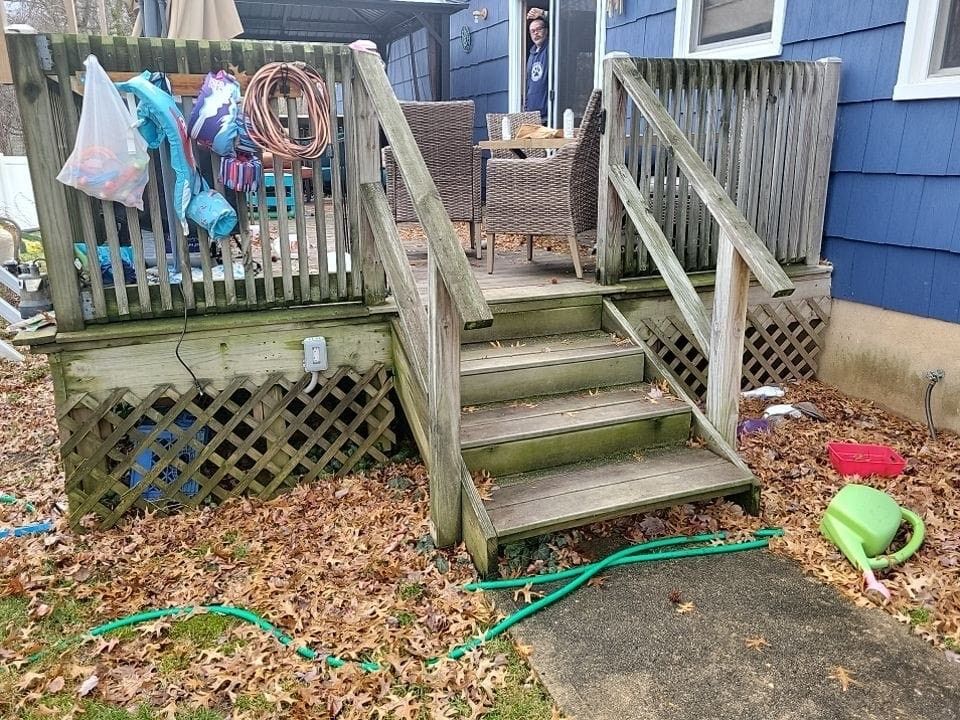 A picture of a brick house with a porch and trees in the background.