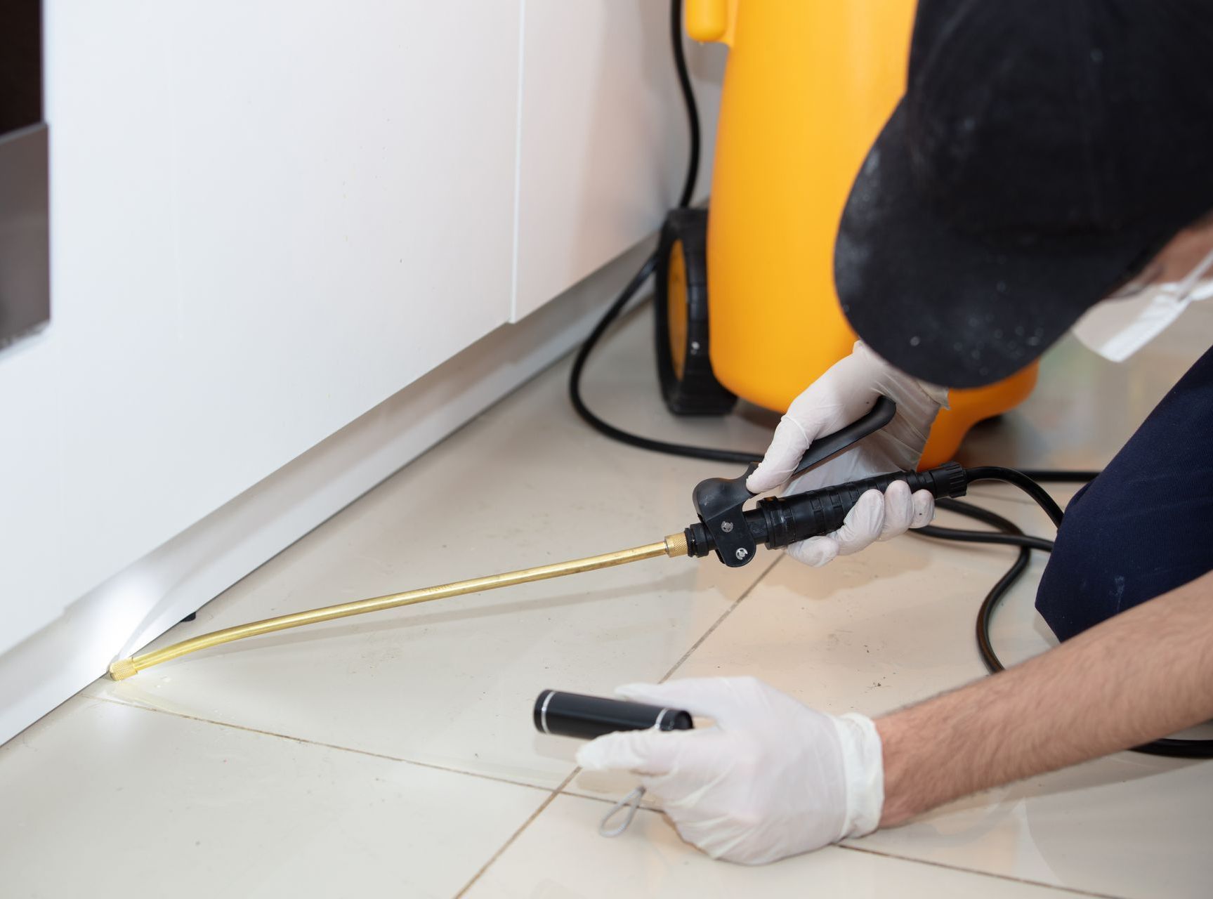 A man is spraying a chemical on the floor.