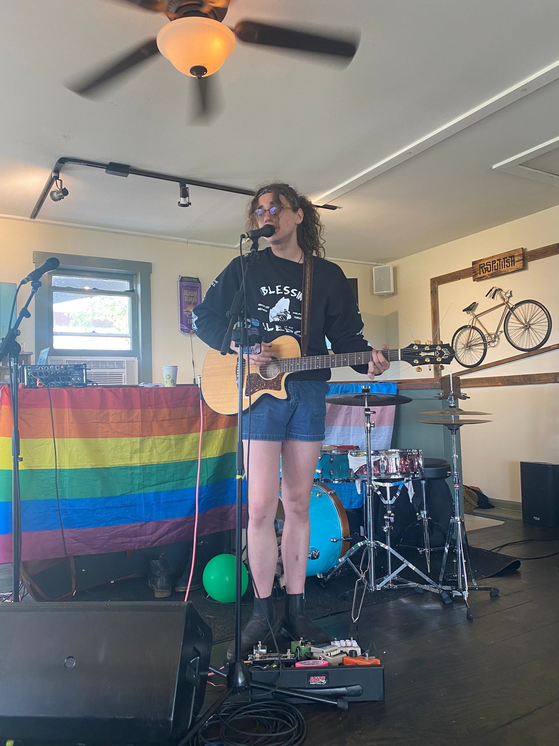 A musician playing guitar and singing after The Wildflower's 2023 Pride Ride.