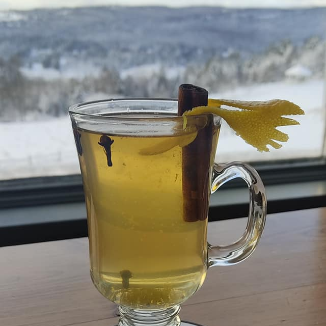 A glass of tea with a cinnamon stick and lemon peel