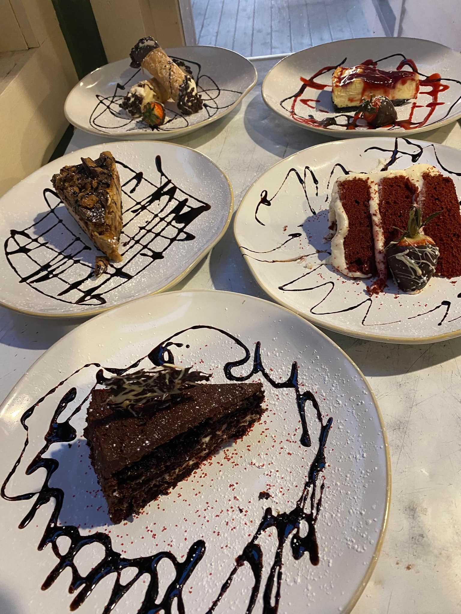 Four desserts, including, chocolate cake, red velvet cake, cheese cake and cannolis.