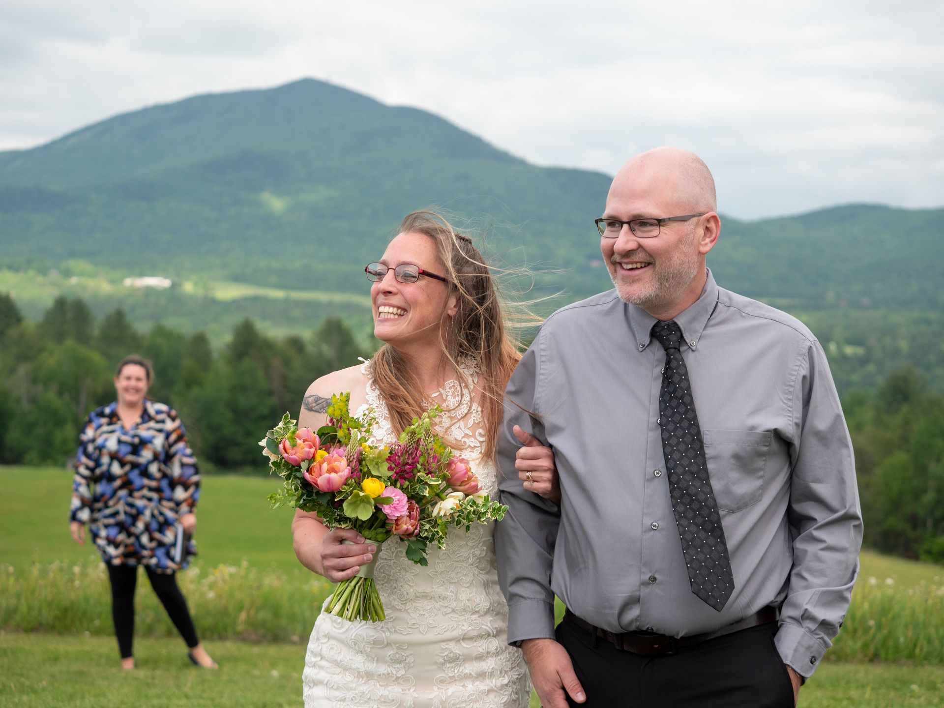 Two newlyweds walking through a field in Vermont after their elopement at The Wildflower.