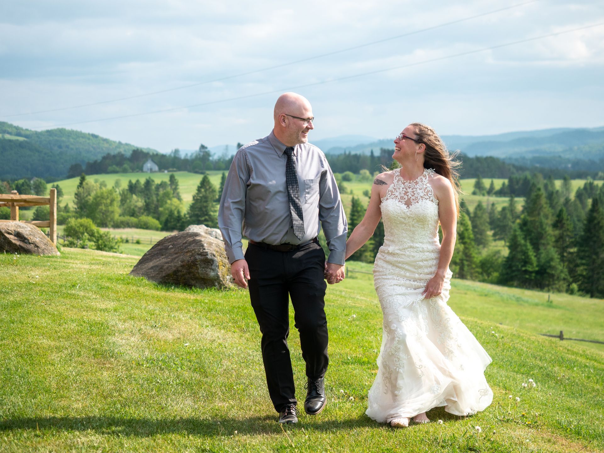 A newlywed couple walking holding hands in a field in Vermont