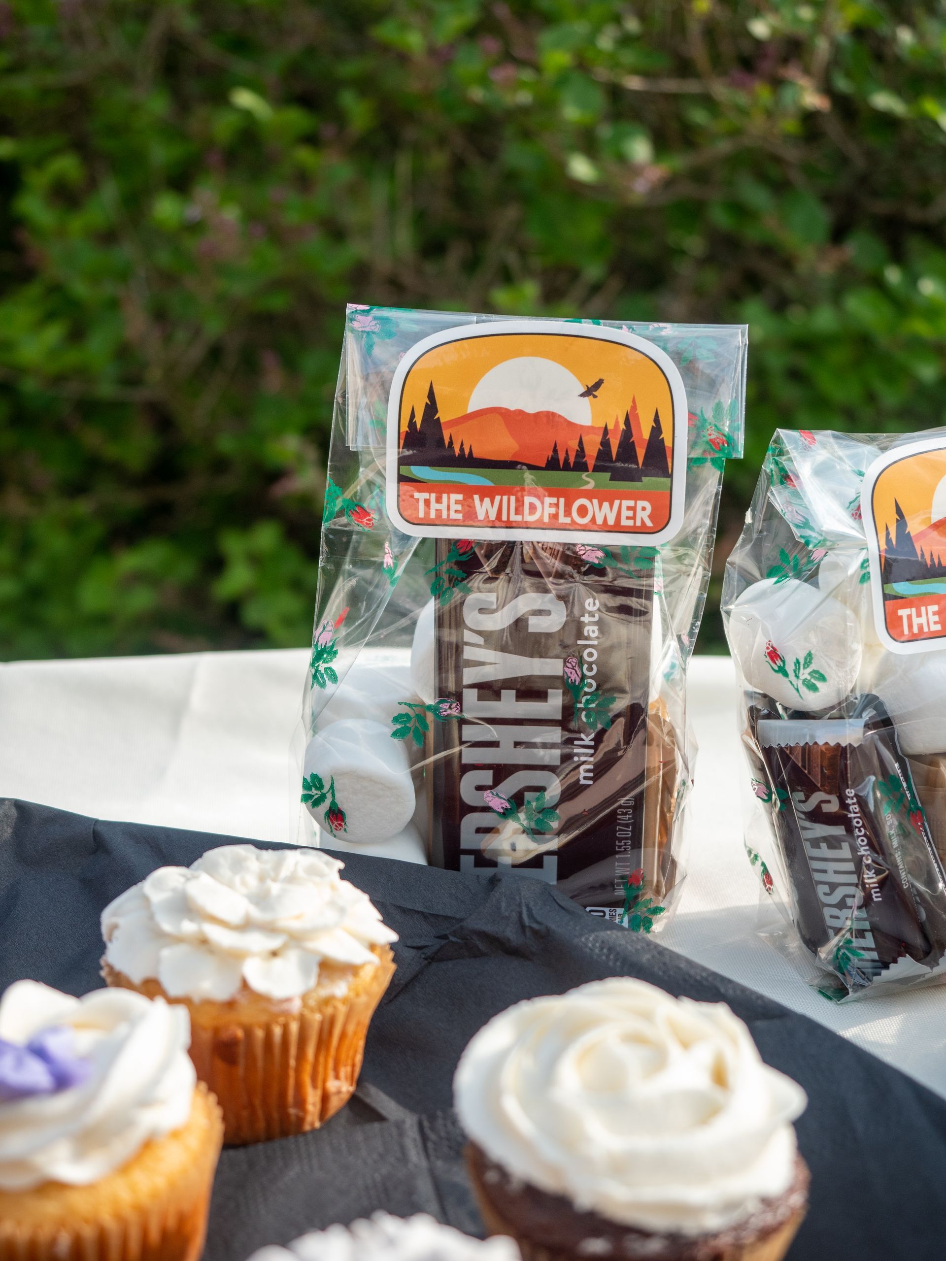 Closeup of cupcakes and a s'mores goodie bag with the Wildflower logo on it.