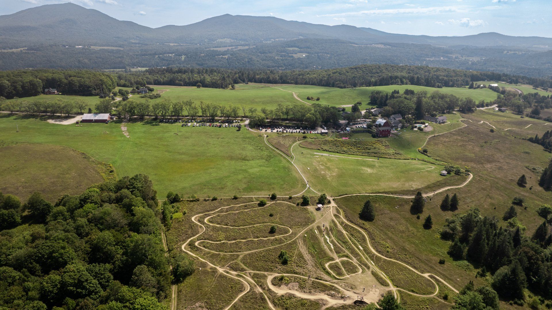 An aerial view of a field with trees and mountains in the background.