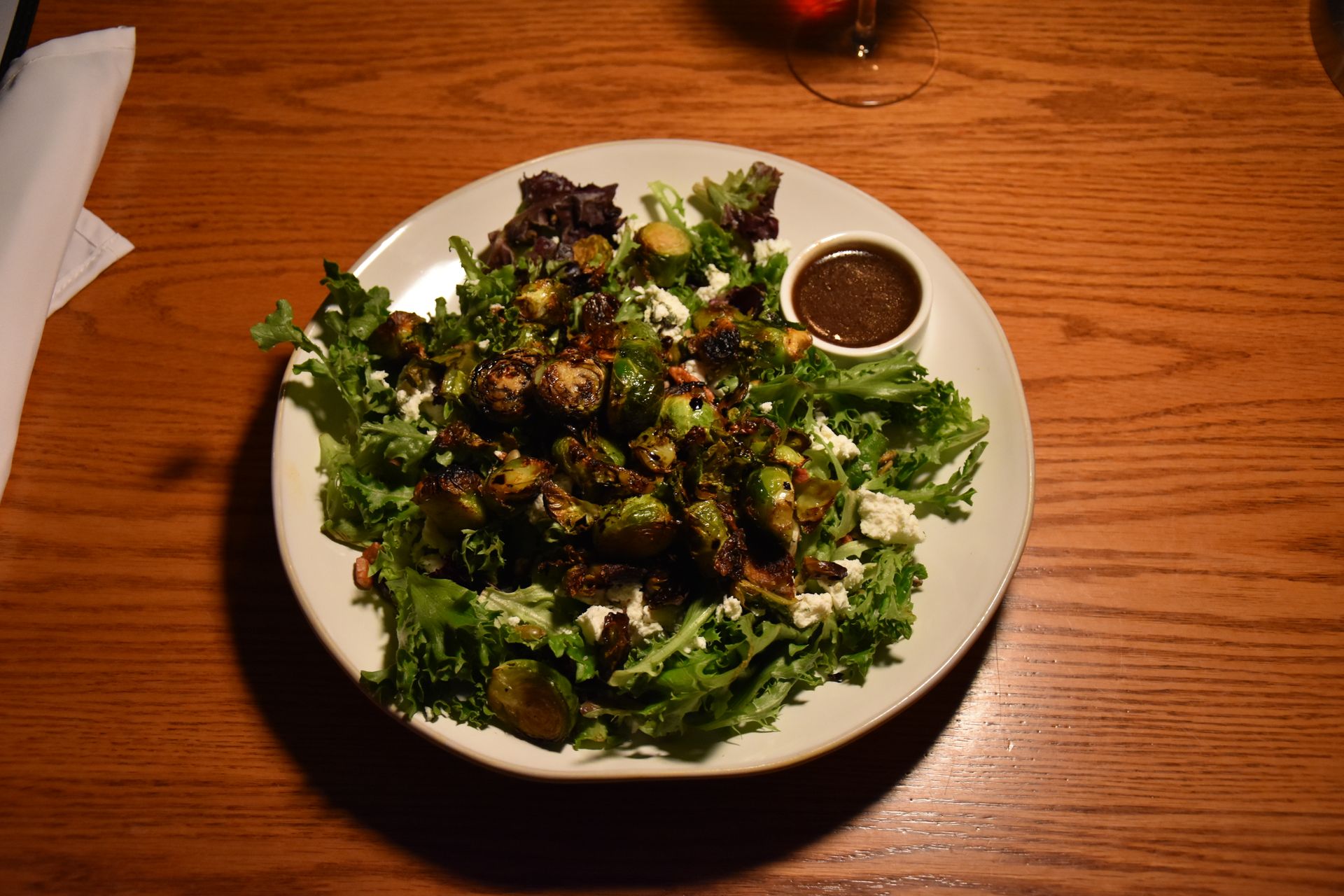 Brussel sprout salad with dressing on white plate on a wooden table.