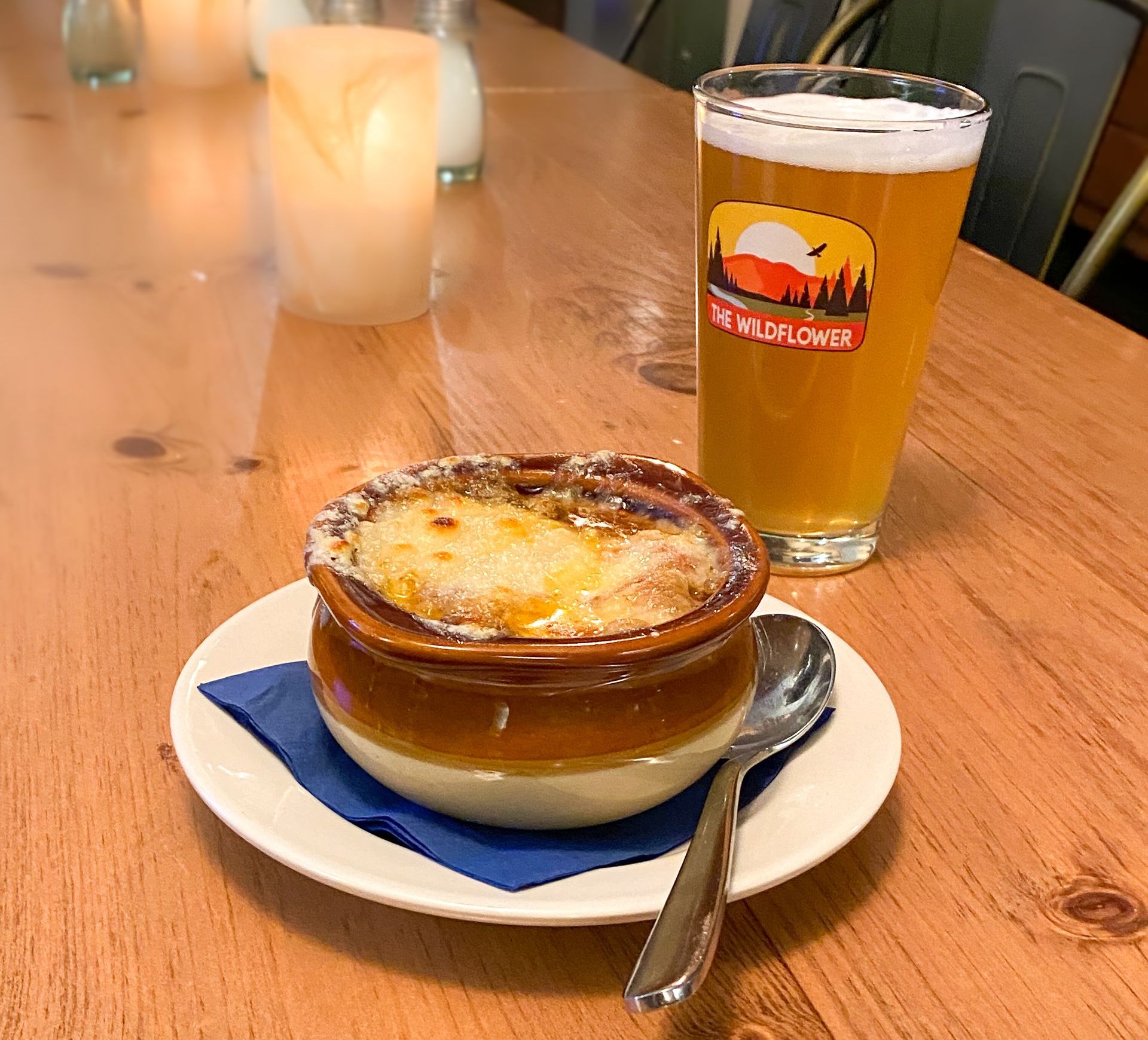 A bowl of  The Wildflower's French Onion Au Gratin soup and a glass of Beer.