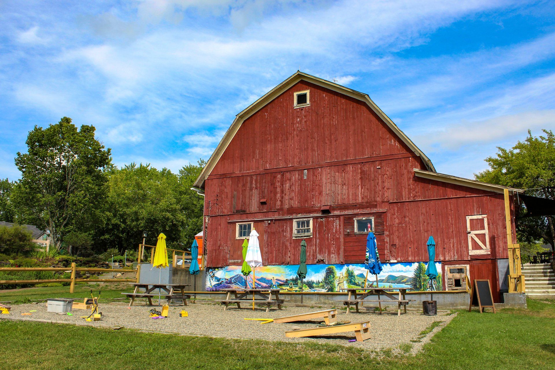 Cornhole boards and picnic tables sit in front of a mural at The Wildflower