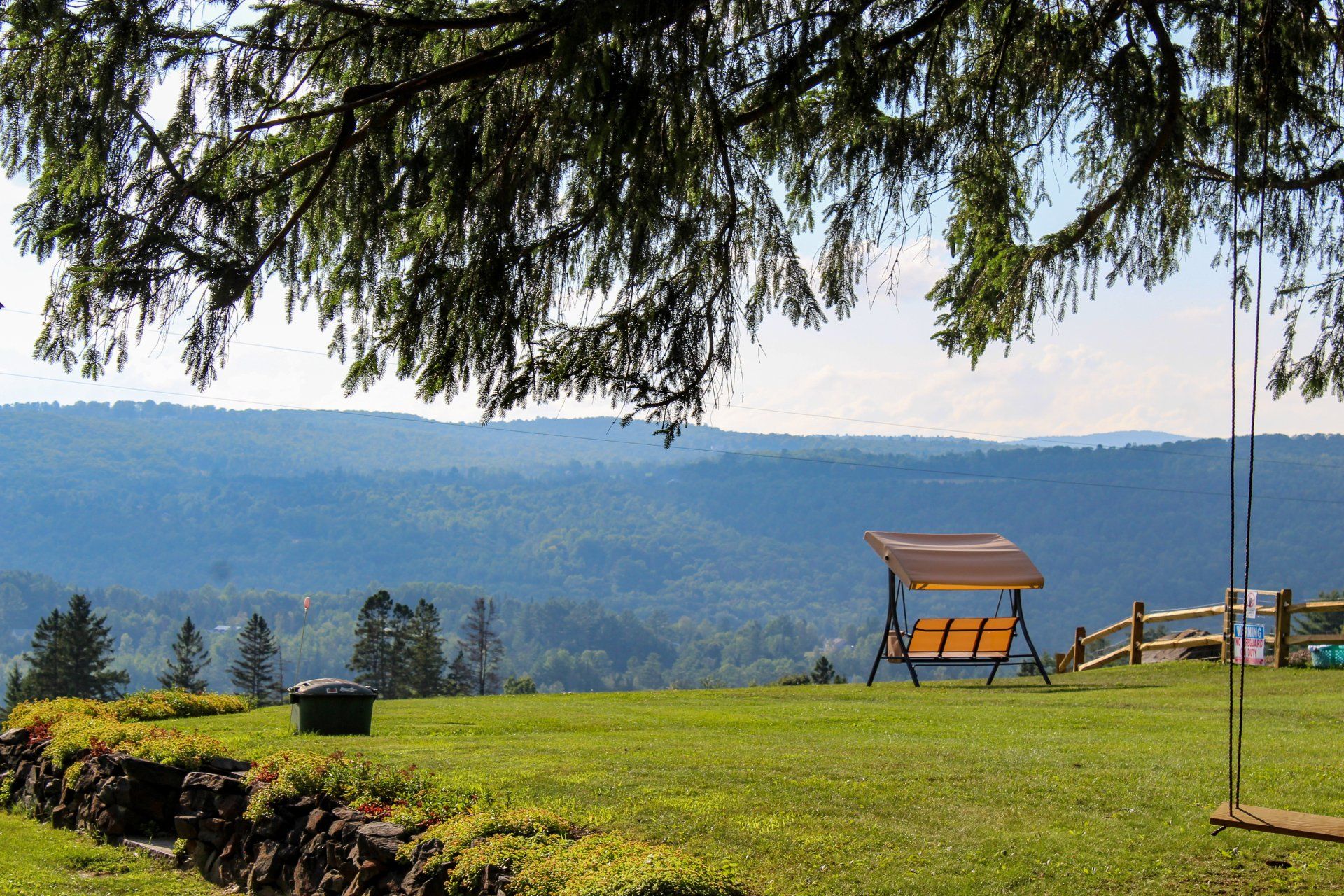 A swing in a grassy field with mountains in the background