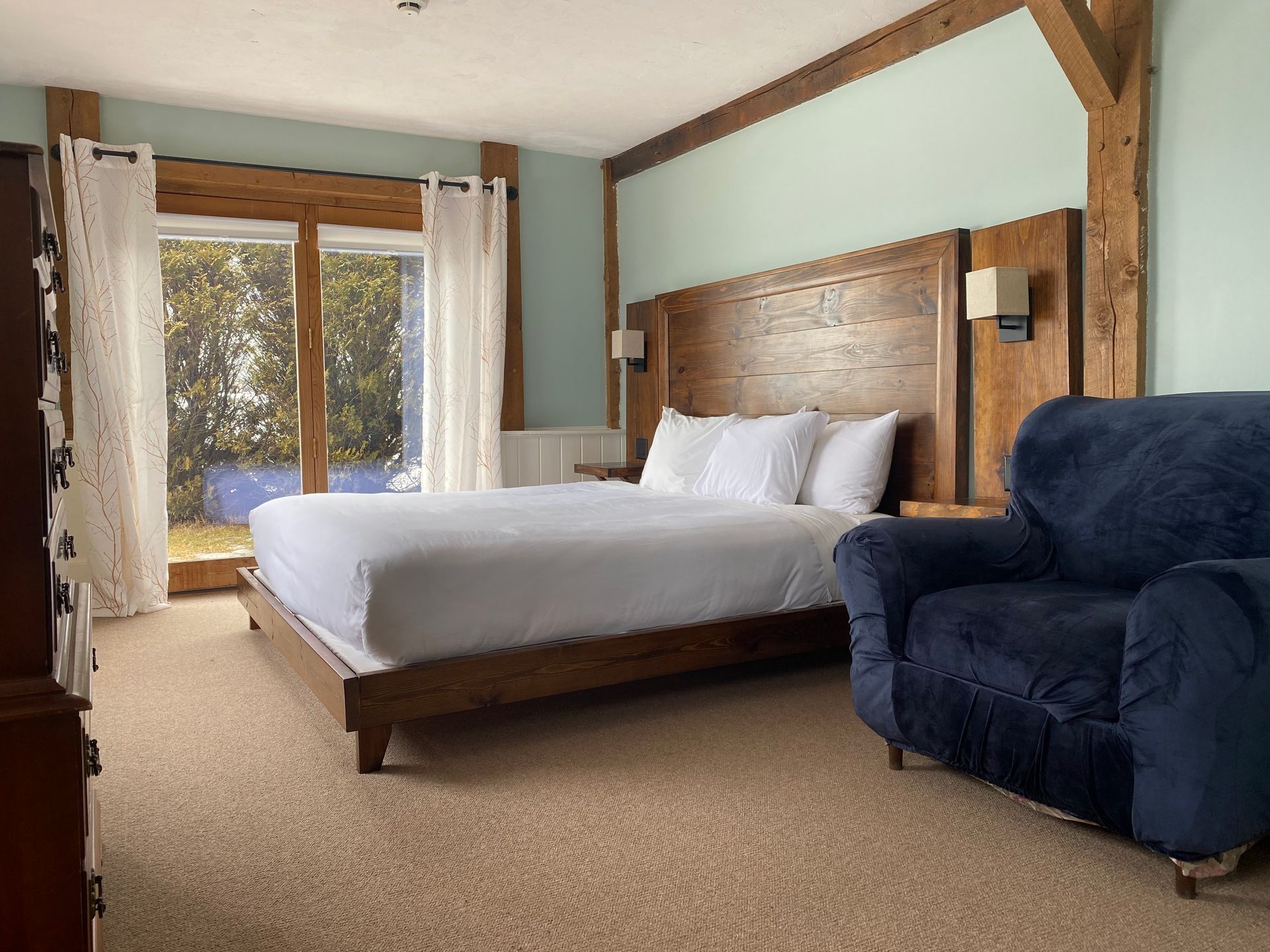 A hotel room with a large bed and a chair