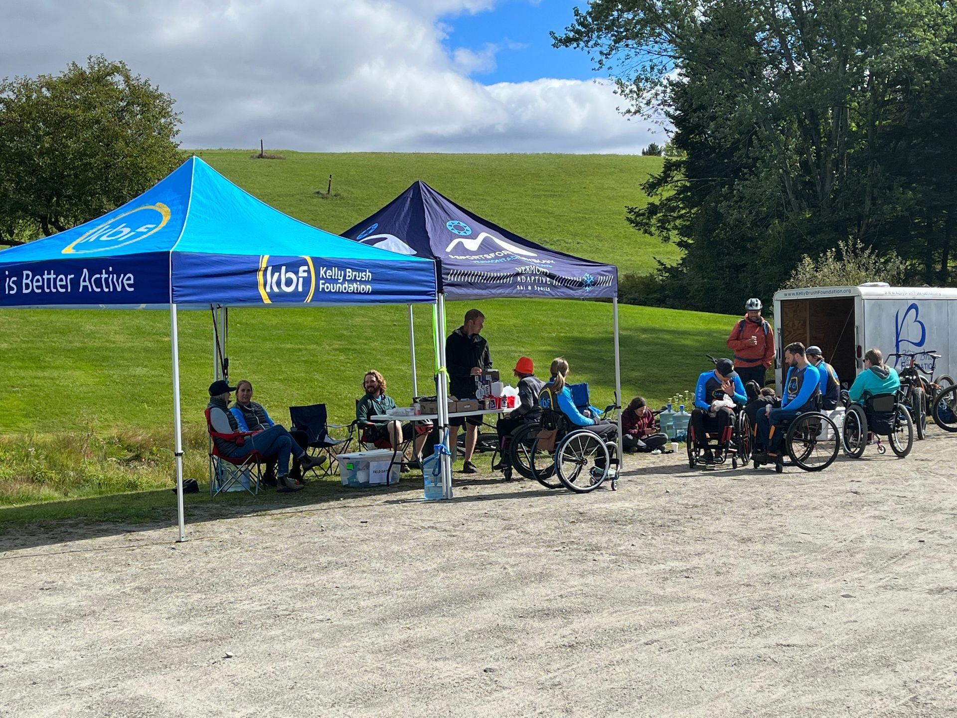 A group of people in wheelchairs gather under event tents at The Wildflower during a non-profit benefit
