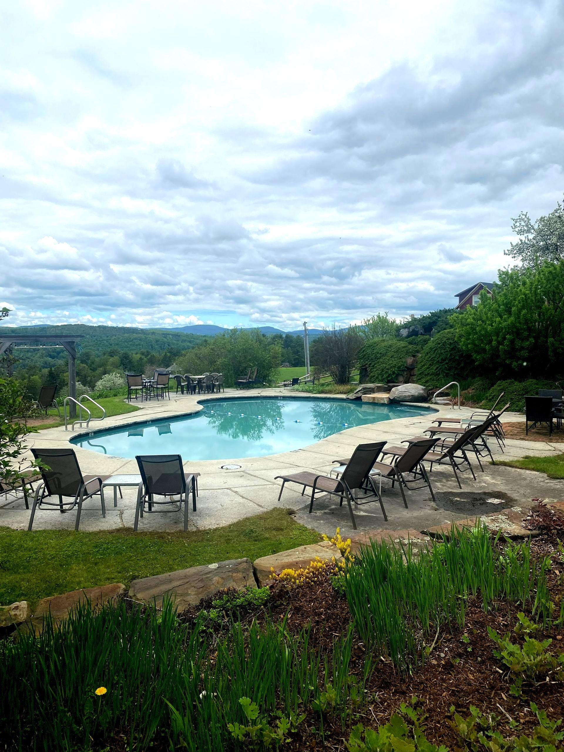 A large swimming pool surrounded by lawn chairs on a cloudy day