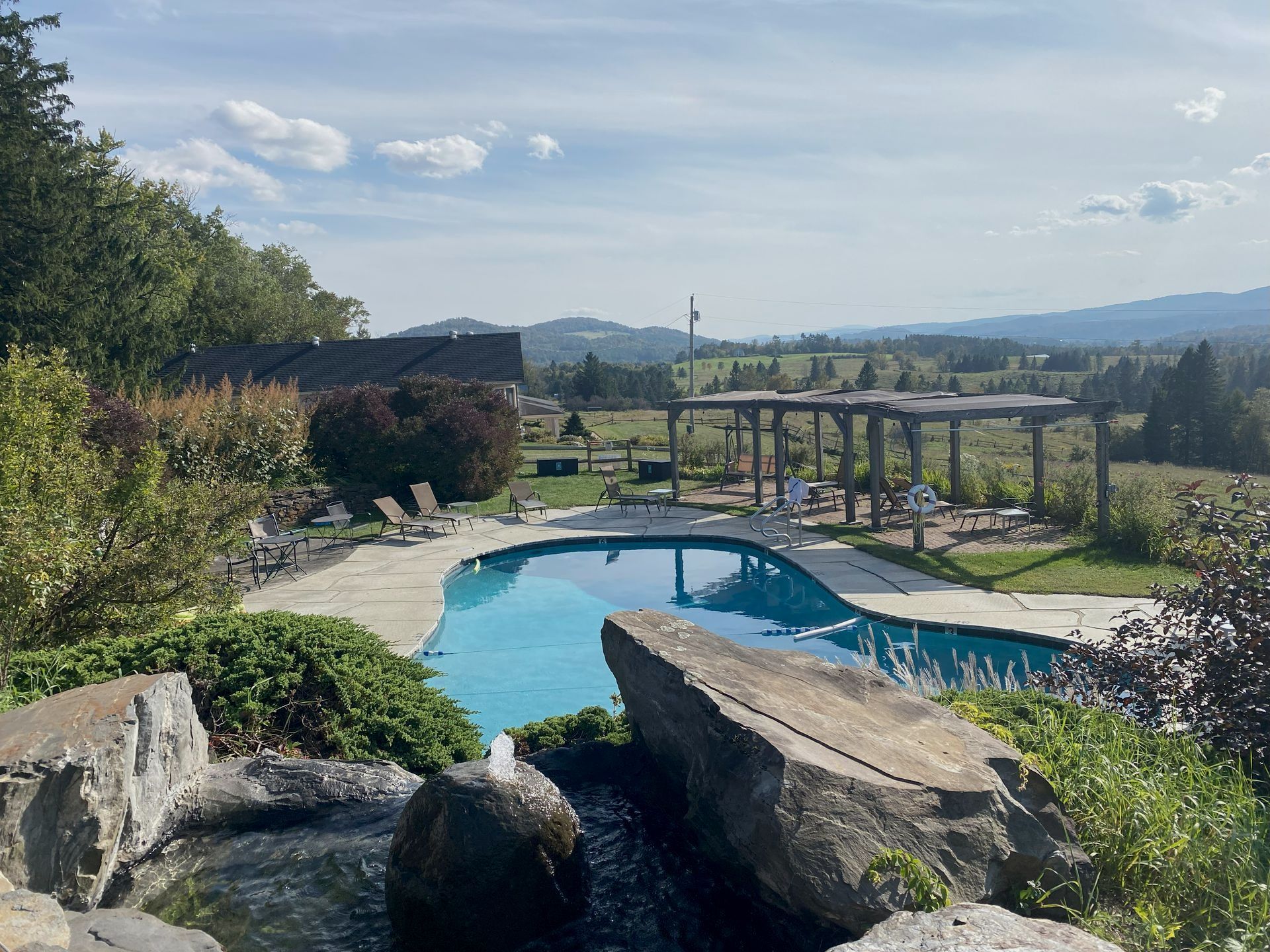 A large swimming pool is surrounded by rocks and trees in Vermont