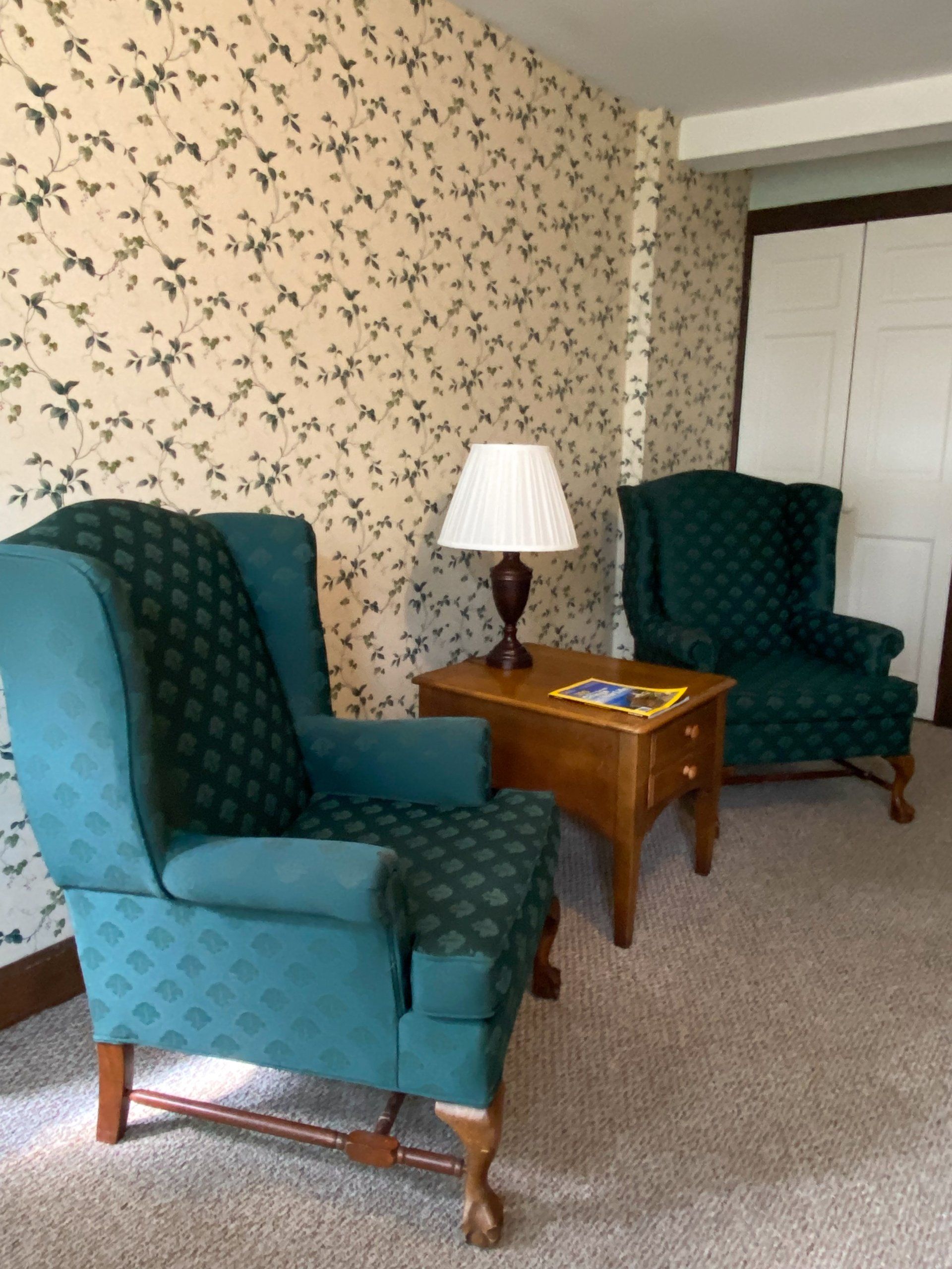 A living room with two green chairs and a lamp