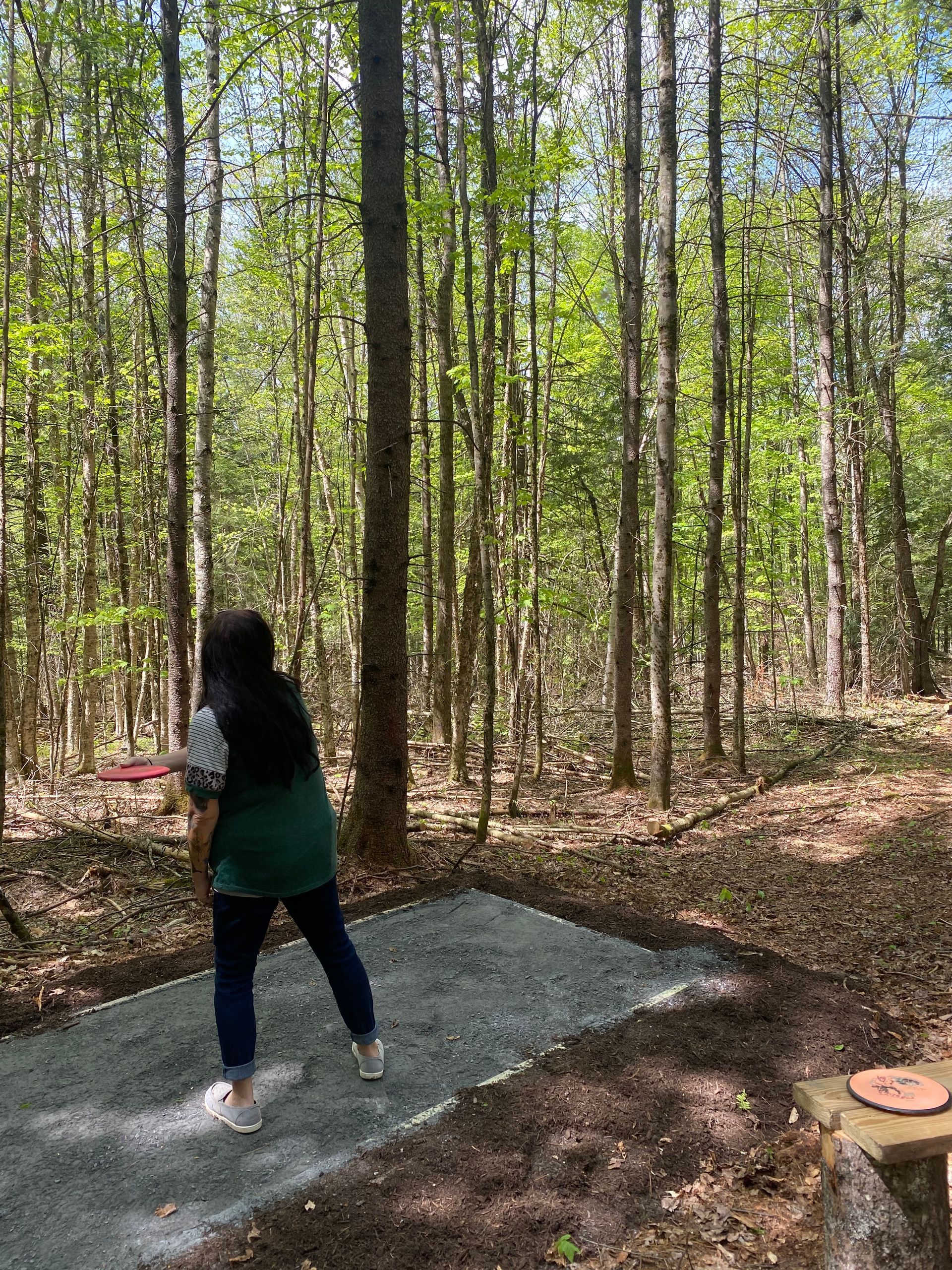A woman is throwing a frisbee in the woods at the Wildflower Inn i Northern VT