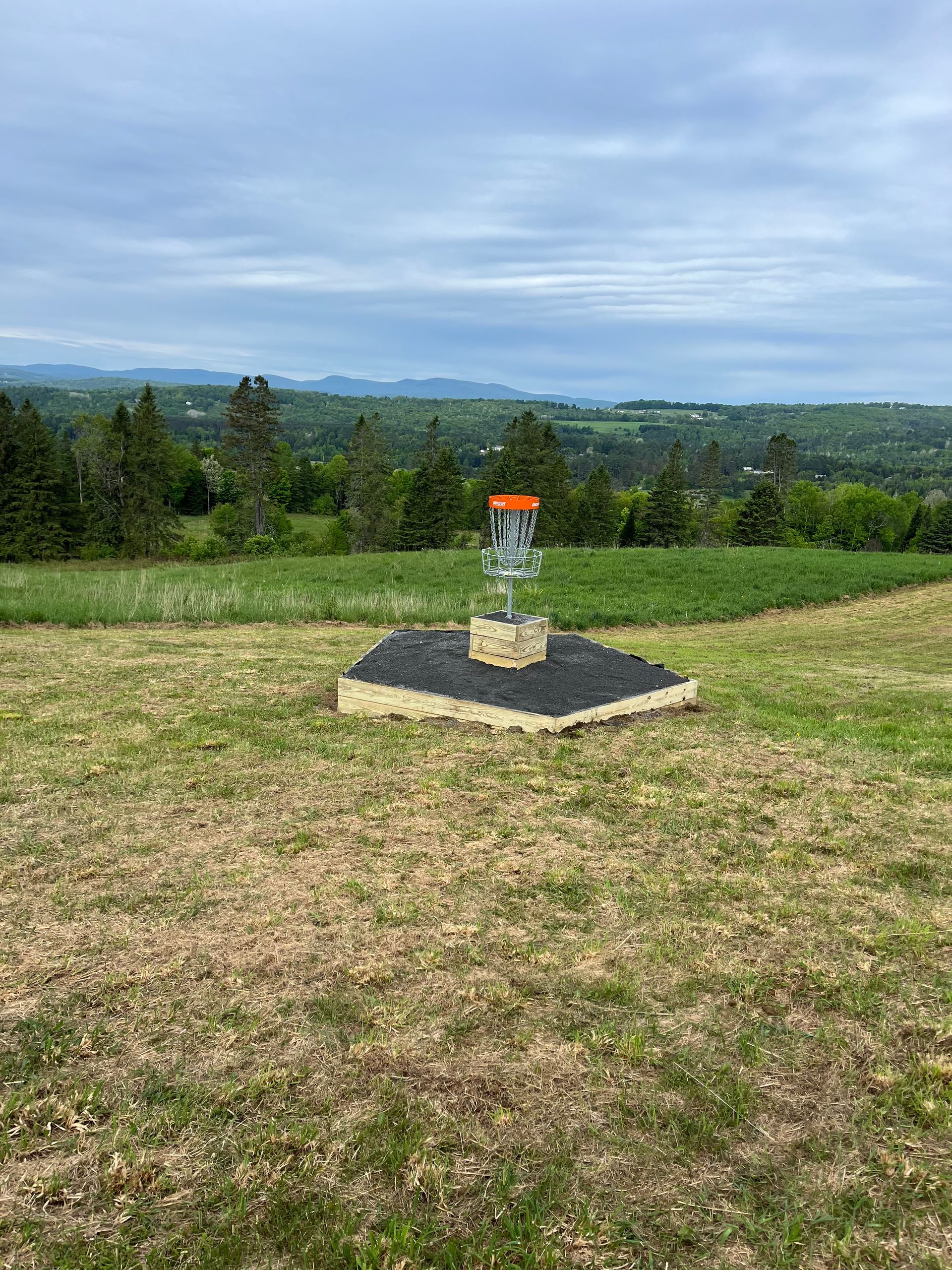 A frisbee/disc golf basket is sitting in the middle of a grassy field at the Wildflower Inn in Vermont