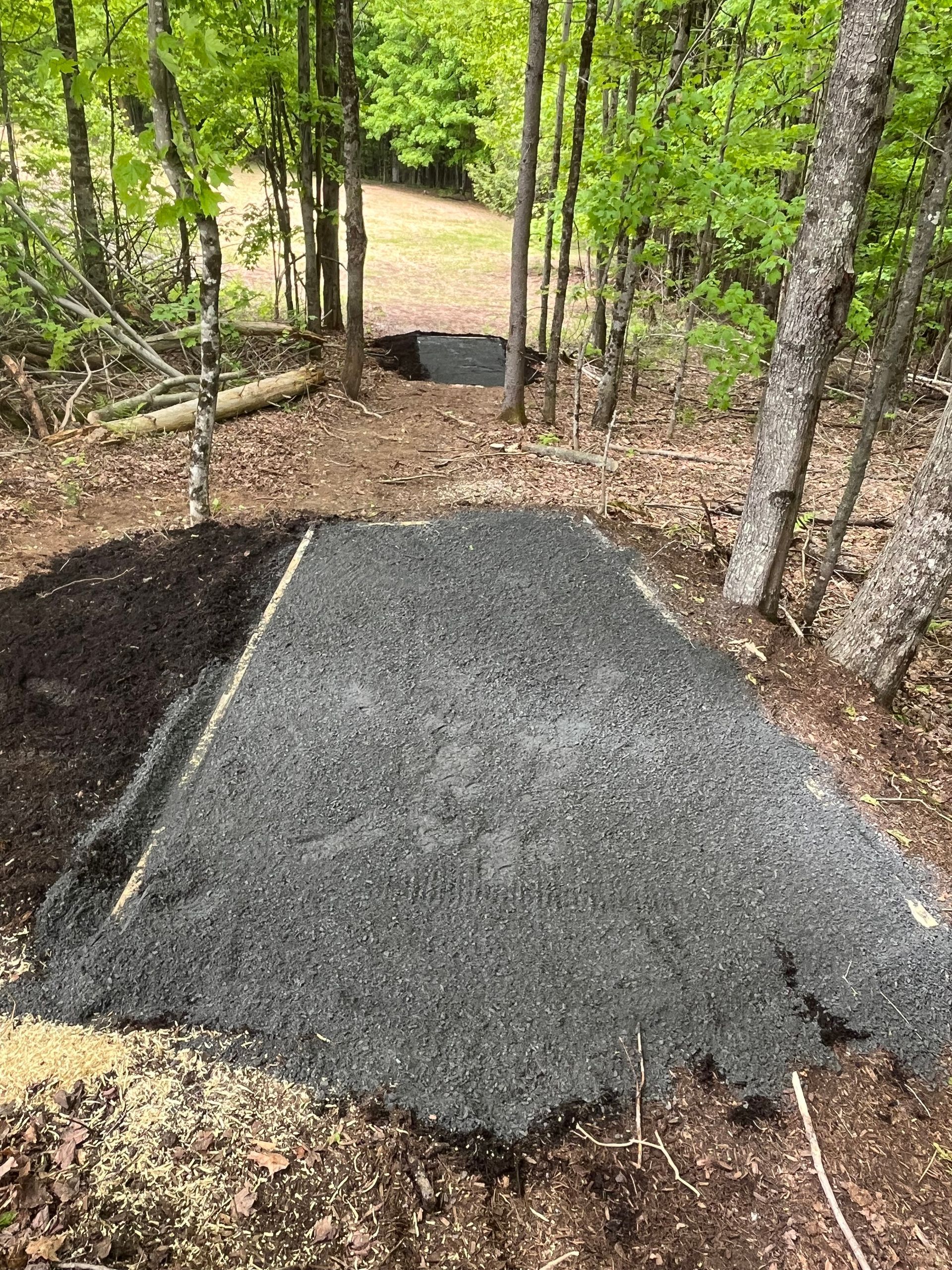 A pile of gravel is sitting in the middle of a forest.