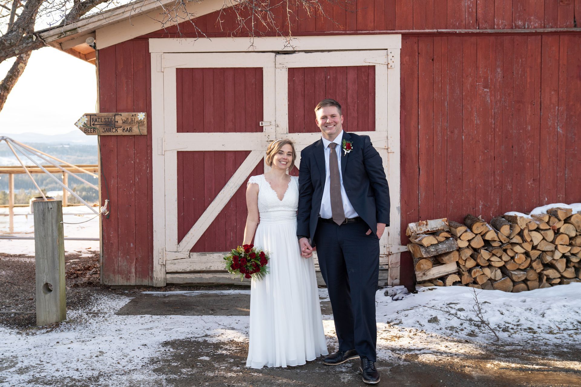 A bride and groom are posing for a picture in front of a red barn.